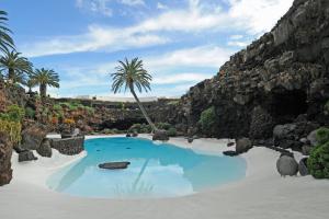 a pool in the middle of a mountain with palm trees at Casa La Barca in Playa Honda