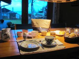 una mesa de madera con platos y tazas. en Tisvildehegn BandB, en Helsinge