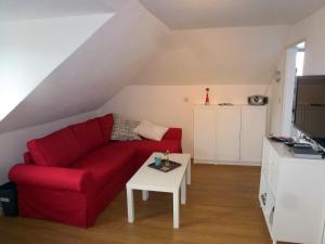 a living room with a red couch and a table at Ferienwohnung Am Runenstein 7 in Busdorf