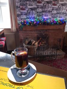 a cup of tea sitting on a table in front of a fireplace at George and Dragon Ashbourne in Ashbourne