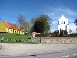 une église, un bâtiment jaune et blanc et une rue dans l'établissement Tisvildehegn BandB, à Helsinge