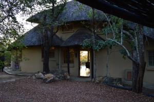 ein Haus mit einem Strohdach und einer Tür in der Unterkunft Kruger River Villas - Mtombo in Marloth Park