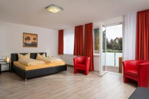a bedroom with a bed and two red chairs at Hotel Nora in Bad Krozingen