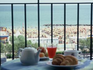 a table with plates of food and a view of a beach at Hotel De La Plage in Rimini
