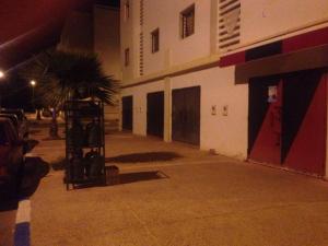 Cozy Appartement في Douar Ben Chellal: موقف سيارات فارغ بجانب مبنى في الليل