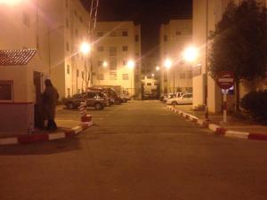 uma rua à noite com carros estacionados num parque de estacionamento em Cozy Appartement em Douar Ben Chellal