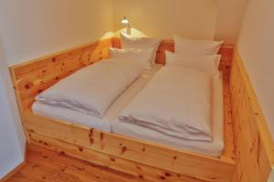 una cama de madera con almohadas blancas. en Landgasthof Weberhans en Harburg