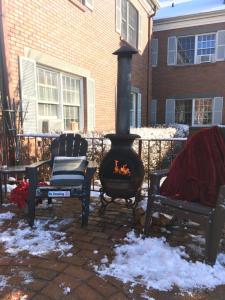 una chimenea en un patio con 2 sillas y nieve en Colts Neck Inn Hotel en Colts Neck