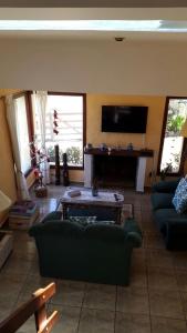 a living room with a green couch and a tv at Piriápolis Corralejo in Piriápolis