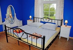 1 dormitorio con 1 cama con espejo y paredes azules en Ferienwohnungen im Gutshaus Gnies en Gnies