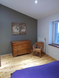 a bedroom with a bed and a wooden dresser at Le Perron in Lézigneux