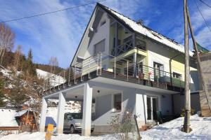a white house with a balcony in the snow at Apartment Leposa in Kranjska Gora