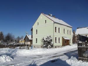 un gran edificio blanco con nieve en el suelo en Penzion, apartmany Florian en Horní Blatná