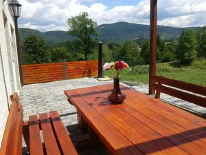 a vase of flowers on a wooden table with benches at Holiday Home Lipa in Vrbovsko