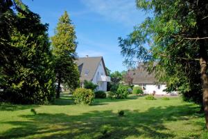 una casa en un patio con árboles y césped en Ferienwohnungen an der Hagenschen, en Middelhagen