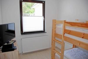 ein Schlafzimmer mit zwei Etagenbetten und einem Fernseher in der Unterkunft NEU - Ferienhaus mit Sonnenterrasse in Ostseebad Sellin + 5 Fotos