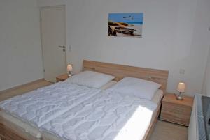 オストゼーバート・ゼリンにあるNEU _ Ferienhaus mit Sonnenterrasseのベッドルーム(白い大型ベッド、ランプ2つ付)