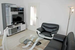 ein Wohnzimmer mit einem Sofa, 2 Stühlen und einem TV in der Unterkunft NEU - Ferienhaus mit Sonnenterrasse in Ostseebad Sellin
