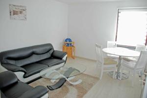 ein Wohnzimmer mit einer schwarzen Ledercouch und einem Tisch in der Unterkunft NEU - Ferienhaus mit Sonnenterrasse in Ostseebad Sellin