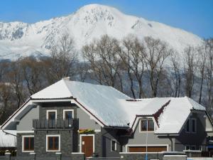 a house in front of a snow covered mountain at TaTanKa apartments in Batizovce