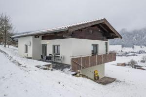 een klein huis in de sneeuw met een houten dak bij Chalet Strobl in Walchsee