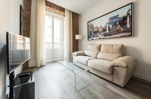 ein Wohnzimmer mit einem Sofa und einem Glastisch in der Unterkunft Puerta Del Sol City Center in Madrid