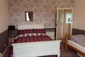 a bedroom with a white bed with a plaid blanket at Bannockburn Inn in Helmsdale