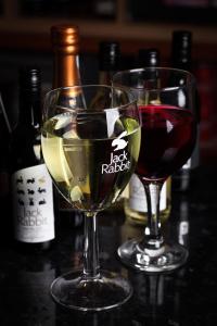 two glasses of wine on a table with bottles of wine at Bannockburn Inn in Helmsdale