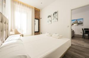 Puerta Del Sol City Center II في مدريد: غرفة نوم بيضاء مع سرير عليه مناشف