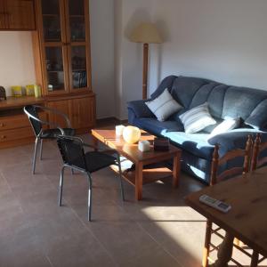 a living room with a blue couch and a table at Apartamento in Los Urrutias