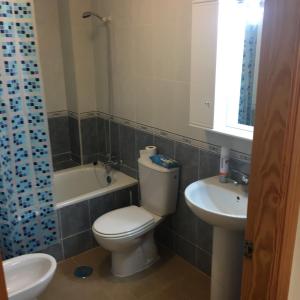 uma casa de banho com um WC, um lavatório e uma banheira em Apartamento em Los Urrutias