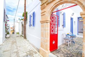 uma porta vermelha numa casa branca com uma mesa numa rua em The red door in Koskinou em Koskinou