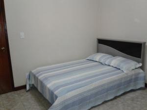 a bedroom with a bed with a blue and white blanket at Casa com Piscina 6 Quartos in Araruama