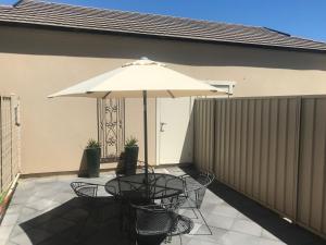 einen Tisch und Stühle unter einem Sonnenschirm auf einer Terrasse in der Unterkunft Travers Street Apartment in Wagga Wagga
