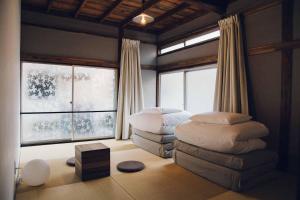 a bedroom with two ottomans in a room with windows at hanare in Tokyo