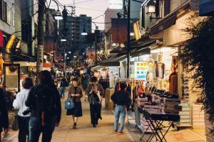 a group of people walking down a street with shops at hanare in Tokyo