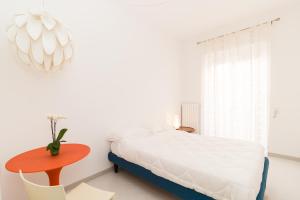 コンヴェルサーノにあるB&B Casa Larucciaの白いベッドルーム(ベッド1台、赤いテーブル付)