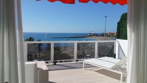 Un balcón con una silla y vistas al océano. en Beachfront Los Cristianos, en Arona