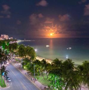 a view of a beach with palm trees and the ocean at night at Apartment NEO 1.0 in Maceió