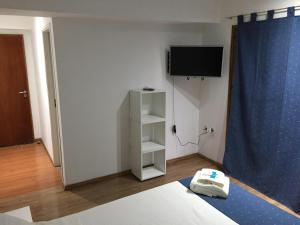 a room with a bed and a tv on the wall at Hosteria Kupanaka in Ushuaia