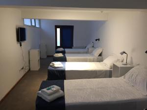 a room with four beds and a flat screen tv at Hosteria Kupanaka in Ushuaia
