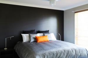 Dormitorio negro con cama con almohada naranja en Ridgemill Estate, en Stanthorpe