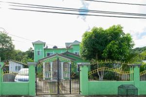 una casa verde con una puerta y un parque infantil en Relax in Sunny Montego Bay, Jamaica, en Montego Bay