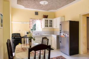 Una cocina con una mesa y un refrigerador de acero inoxidable. en Relax in Sunny Montego Bay, Jamaica, en Montego Bay