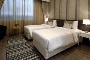 two beds in a hotel room with white sheets at Ratchadamnoen Residence in Bangkok