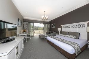 a bedroom with a king sized bed and a bathroom at Grand Mercure Basildene Manor in Margaret River Town