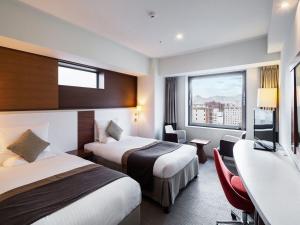 a hotel room with two beds and a window at HOTEL MYSTAYS Sapporo Station in Sapporo