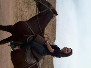 a woman is sitting on a horse at Yurt camp Meiman Ordo in Bokonbayevo