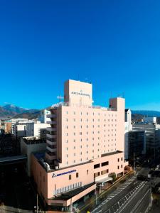 a large white building in a city at Alpico Plaza Hotel in Matsumoto