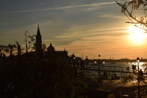 a sunset over a body of water with a clock tower at La Casa del Mercante Veneziano in Venice